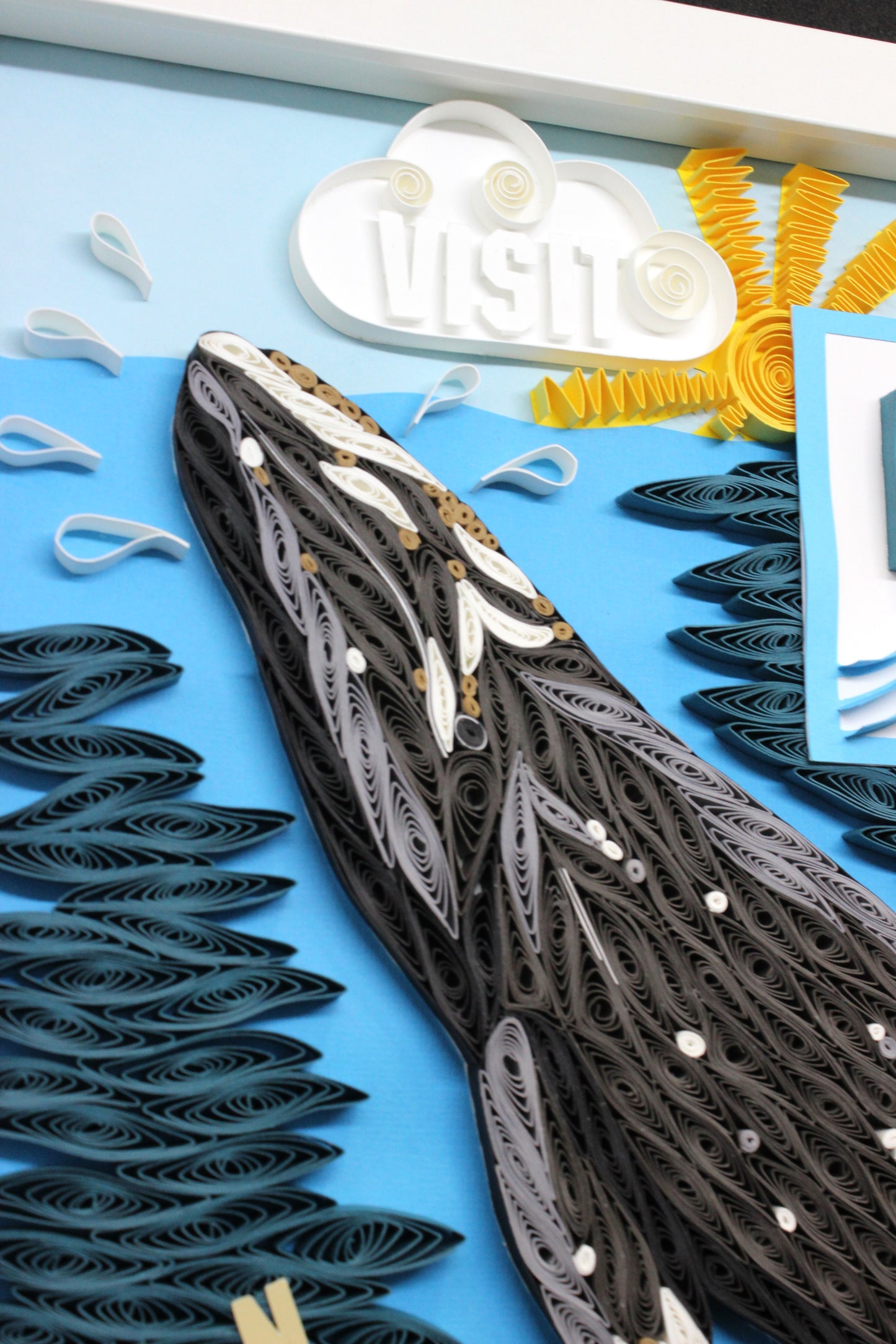 side angle detail of quilled paper gray whale head breaching surface of water