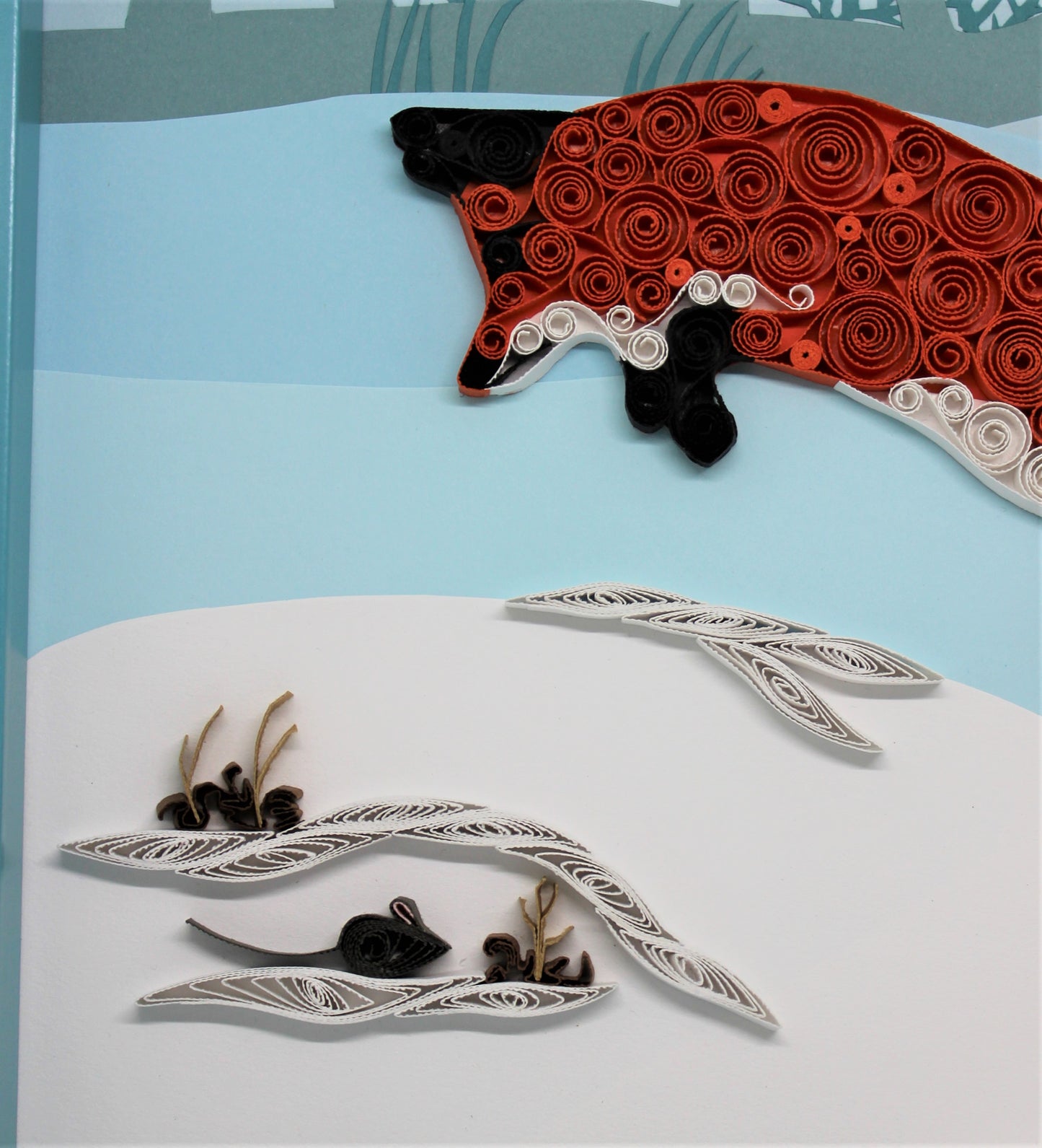 close view of quilled paper red fox pouncing over quilled mouse hidden in a snowbank