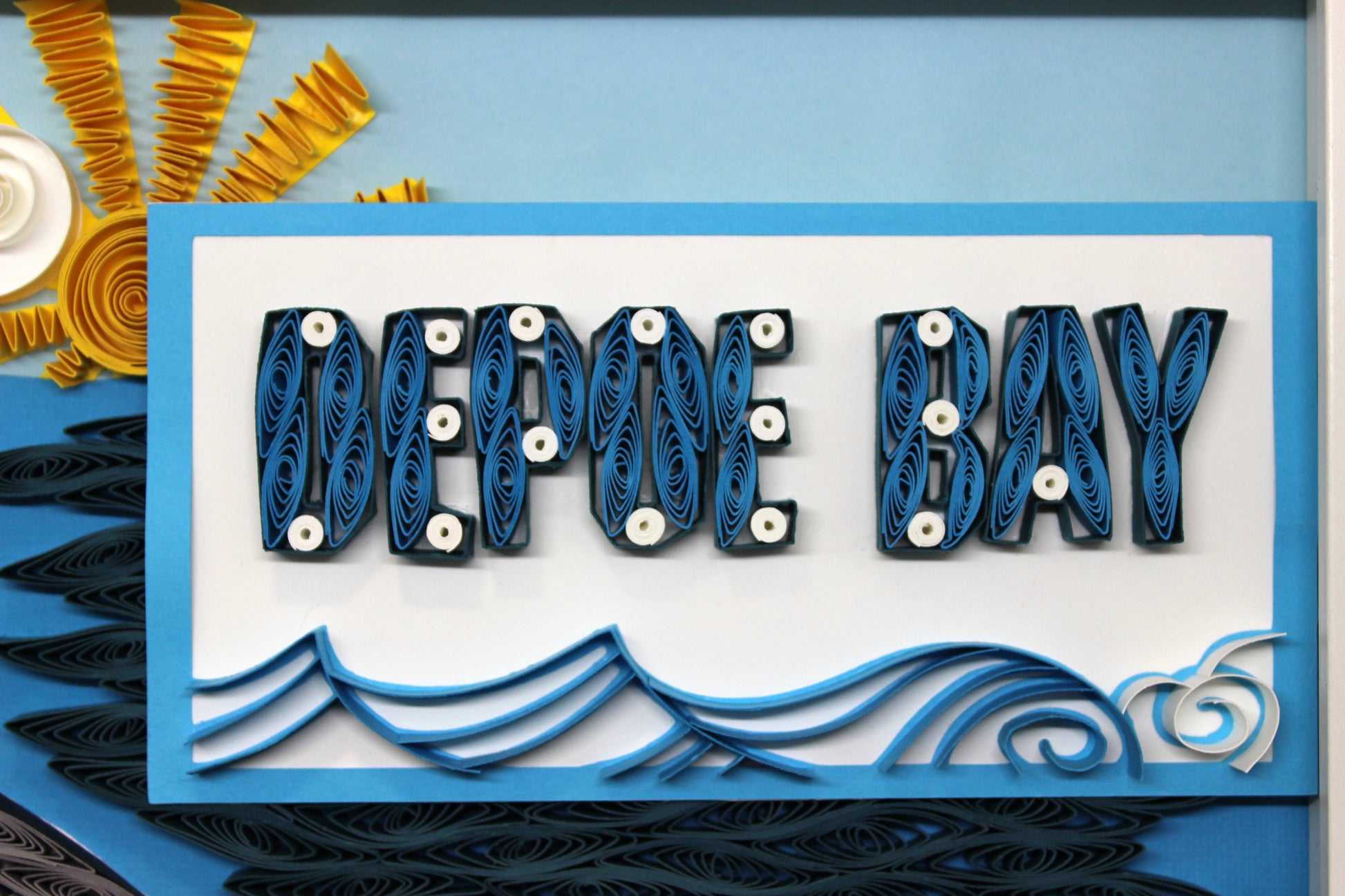 close up detail of quilled "Depoe Bay" sign