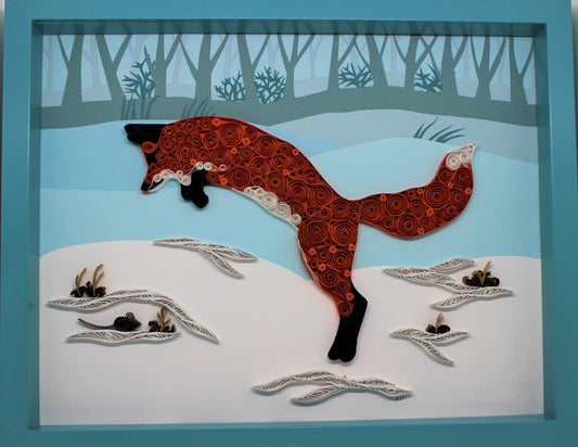paper quilled red fox leaping over a snowy field where a small field mouse hides under a snowbank
